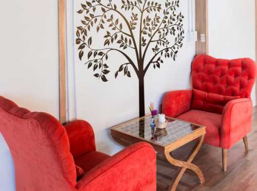 Выбирая черную мягкую мебель, стоит расположить ее на красном овальном ковре, который, в свою очередь, должен быть размещен на темном напольном покрытии