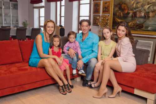 На нем он стоит на фоне памятника, а в руках держит кепку